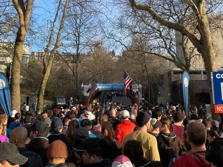 Runners gathered at the 10K start line at Seattle Center under bare trees, an American flag by the arch