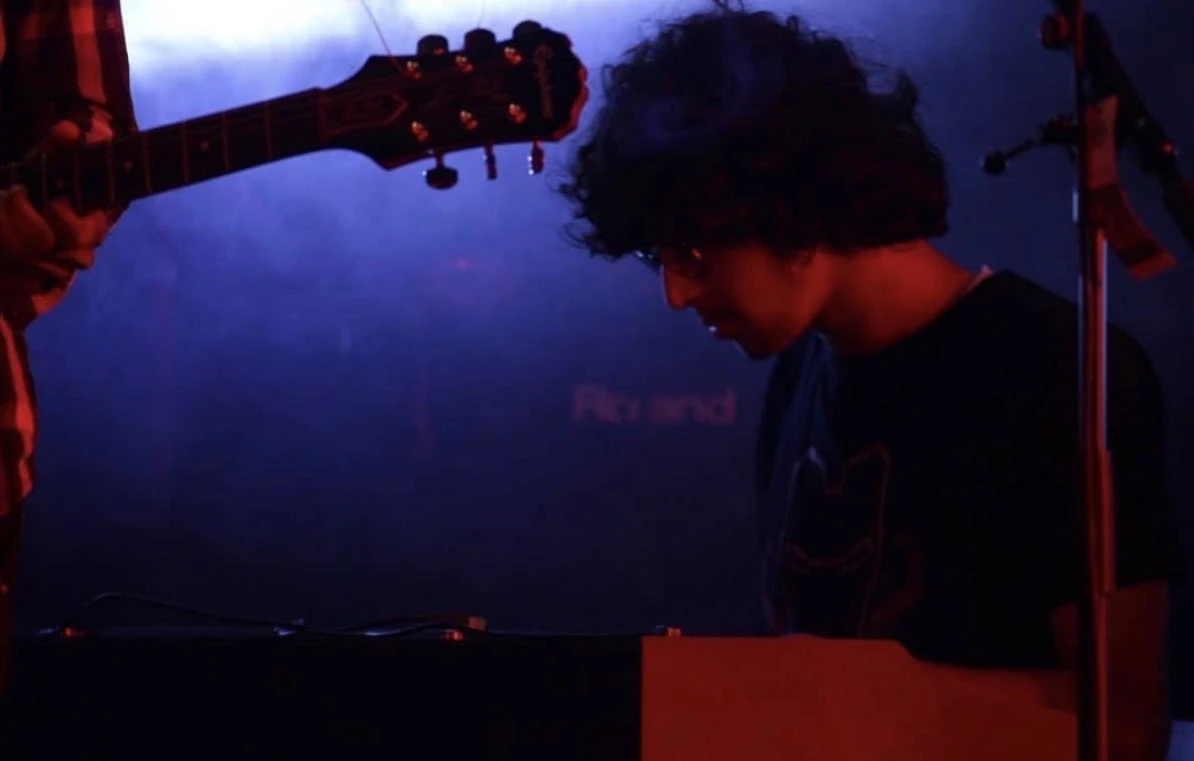 Saksham playing keys on stage under red and blue light